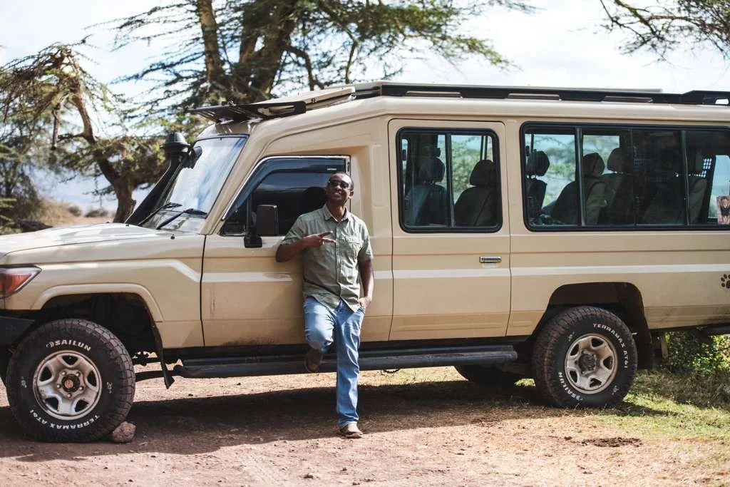 Lucas standing beside his beige safari vehicle